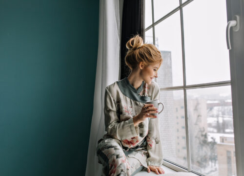 femme avec une tasse devant une fenêtre isolante